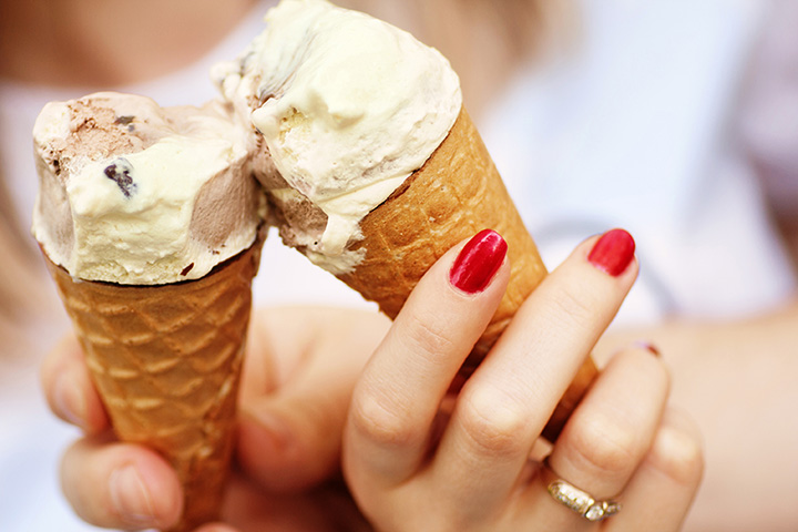 Close up photo of two people cheering their ice cream cones with assorted ice cream flavors.