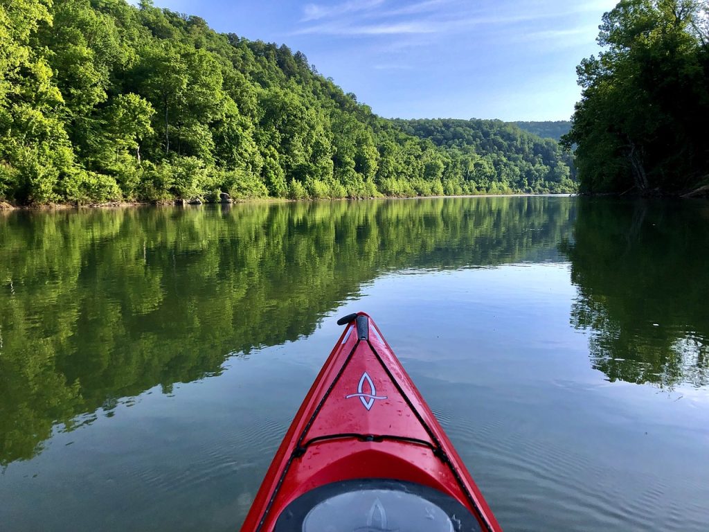Individual is kayaking peacefully down an Arkansas river on a nice sunny day