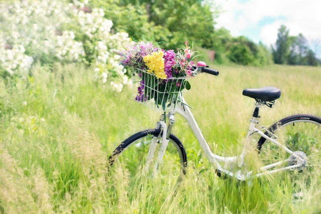 an old school bike with a basket in the front sitting in the middle of a field with tall grass.