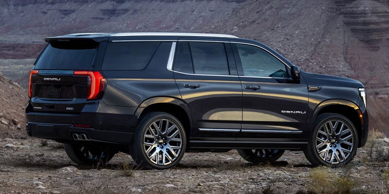 2027 GMC Yukon Denali rear three-quarter exterior view, desert setting
